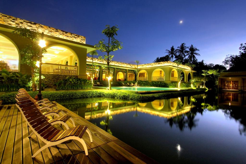 a house with a swimming pool at night at The Westlake Hotel & Resort Yogyakarta in Yogyakarta