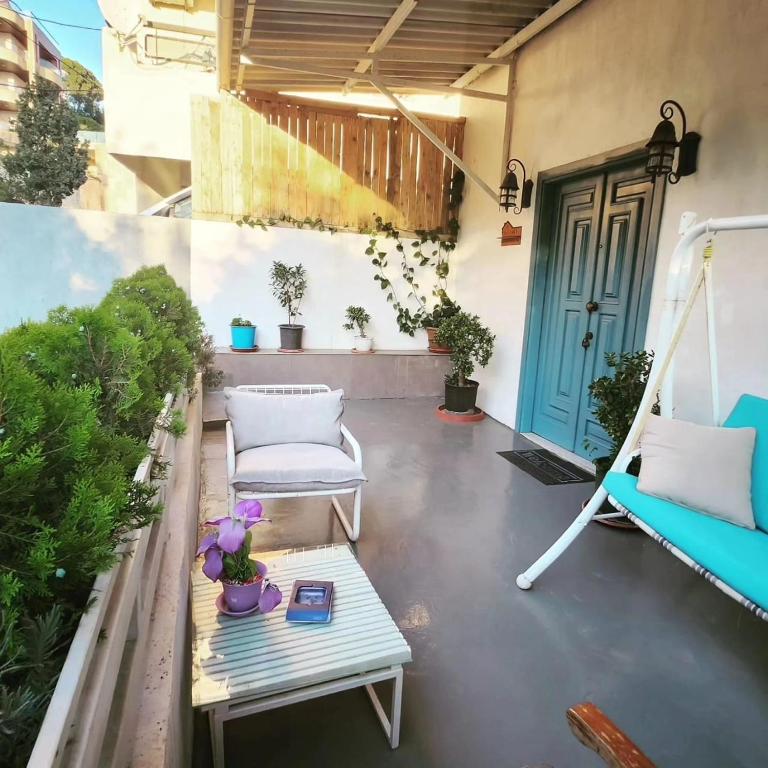 a porch with a swing and a table and a door at Z House Jbeil in Jbeil