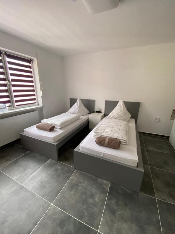 a bedroom with two beds and a window at Modernes 1-Zimmer Apartment mit Küche und Bad in Merzig