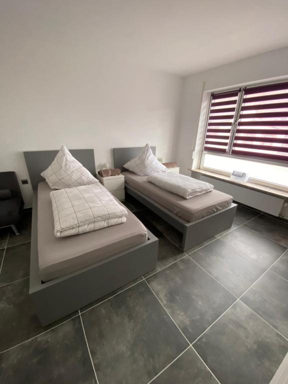 two beds in a room with a window at Moderne 2 Zimmer Wohnung Küche und Bad im Zentrum in Merzig