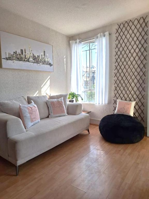 a living room with a white couch and a large window at Hermoso departamento cómodo in San Lorenzo Tetlixtac