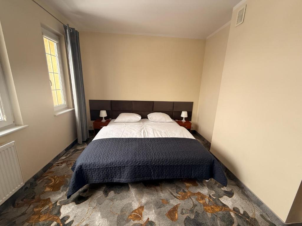 a bedroom with a bed and two windows at Hotel Gryf in Kościerzyna