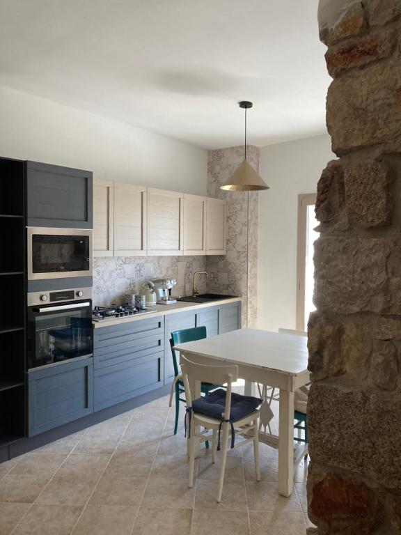 a kitchen with a white table and a table and chairs at Sa dommu de pedra in Santa Maria Navarrese