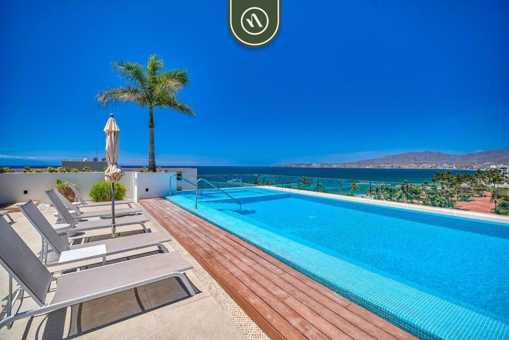 a swimming pool with lounge chairs and the ocean at 2BR Condo with Rooftop Pool - 2 Min Walk to Beach in Bucerías