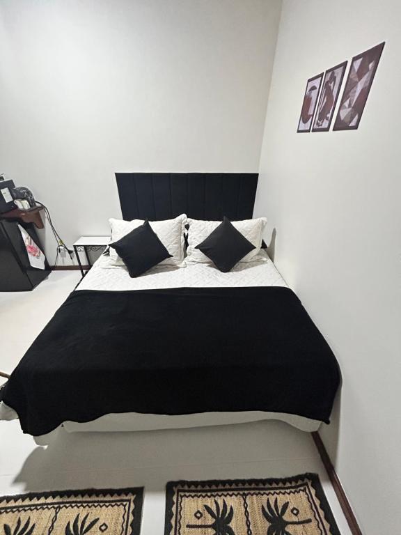 a bedroom with a black and white bed with pillows at Riso Suítes - Jantar Romântico in Santo Antônio do Pinhal