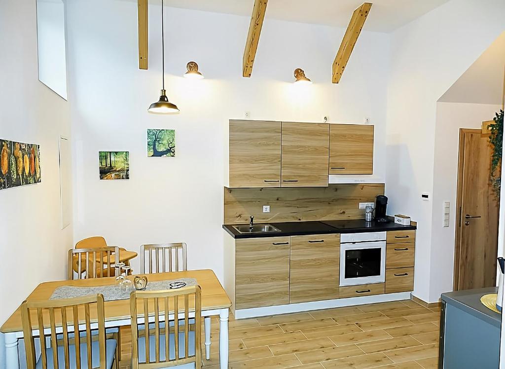 a kitchen with wooden cabinets and a table with chairs at Ferienwohnung Schusternagerl in Simbach