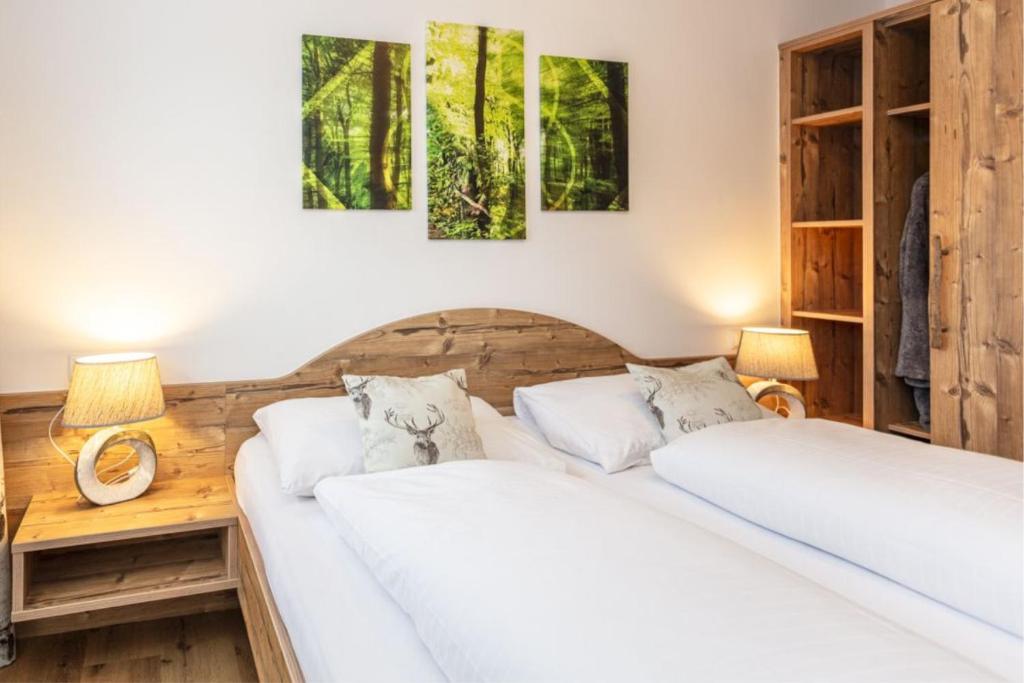 two beds in a bedroom with two lamps on a table at Neuhof Appartements in Maishofen