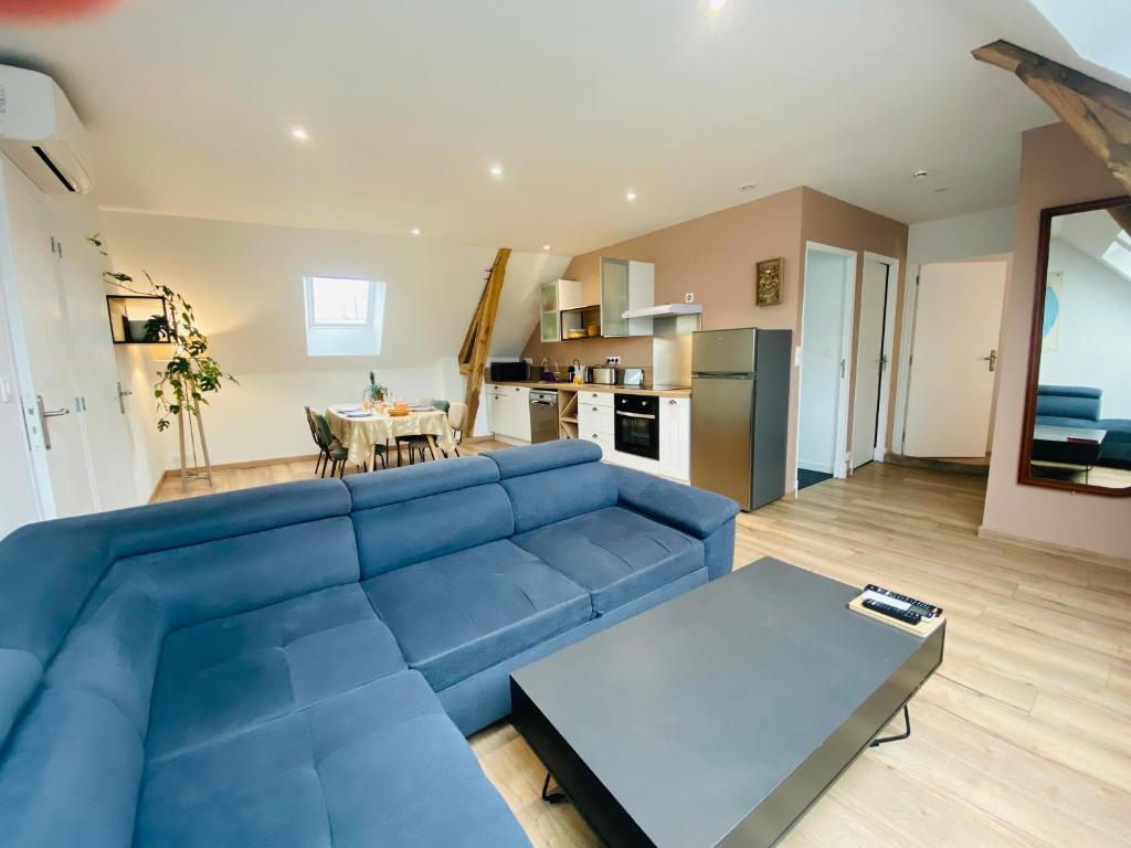 a blue couch in a living room with a table at Le Grand Francillon in Villebarou