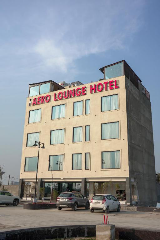 a large hotel with cars parked in a parking lot at The Aero Lounge Hotel 2kms From Airport in Amritsar