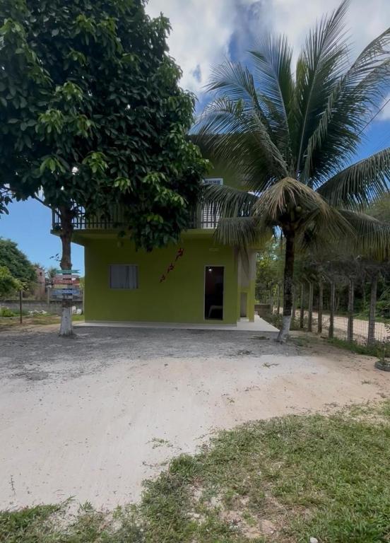a green house with a palm tree in front of it at Pousada Bela Rosa in Santa Cruz Cabrália