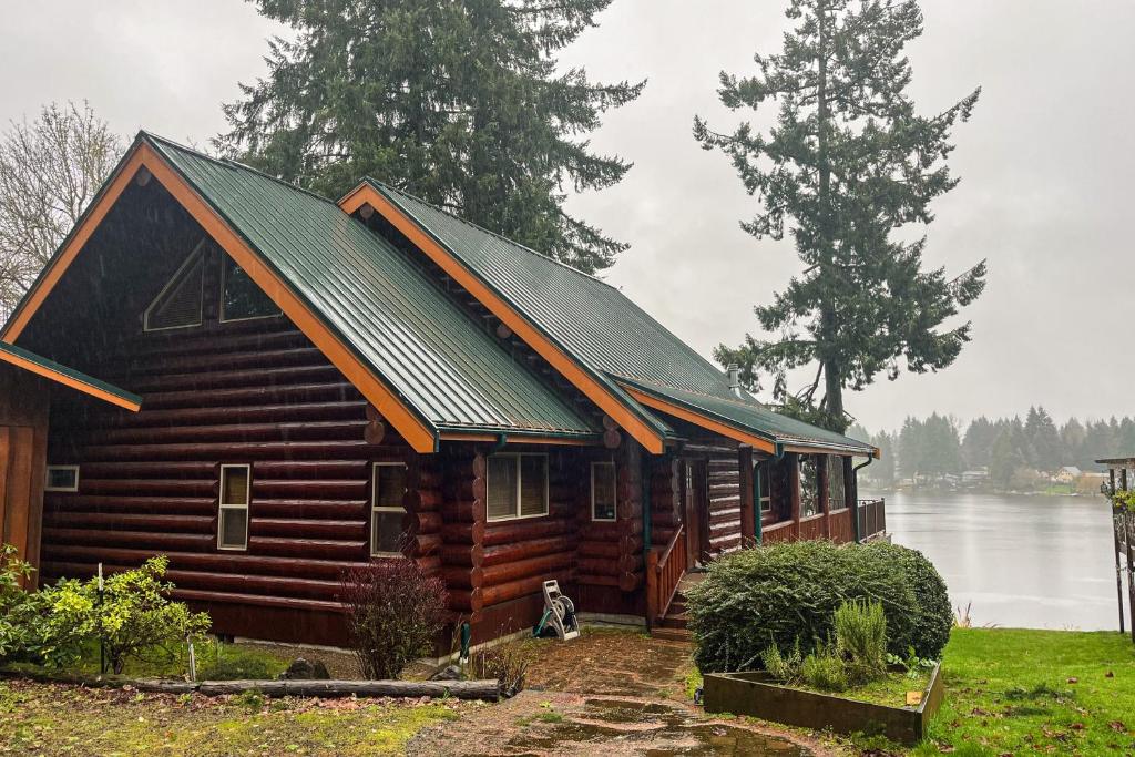 a log cabin with a metal roof on a lake at The Dockside Gamehouse in Olympia