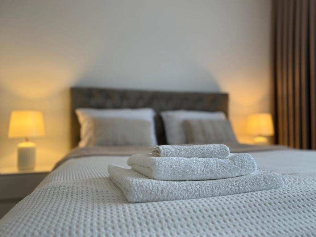 two towels are stacked on a bed with two lamps at Bella stan na dan in Široki Brijeg