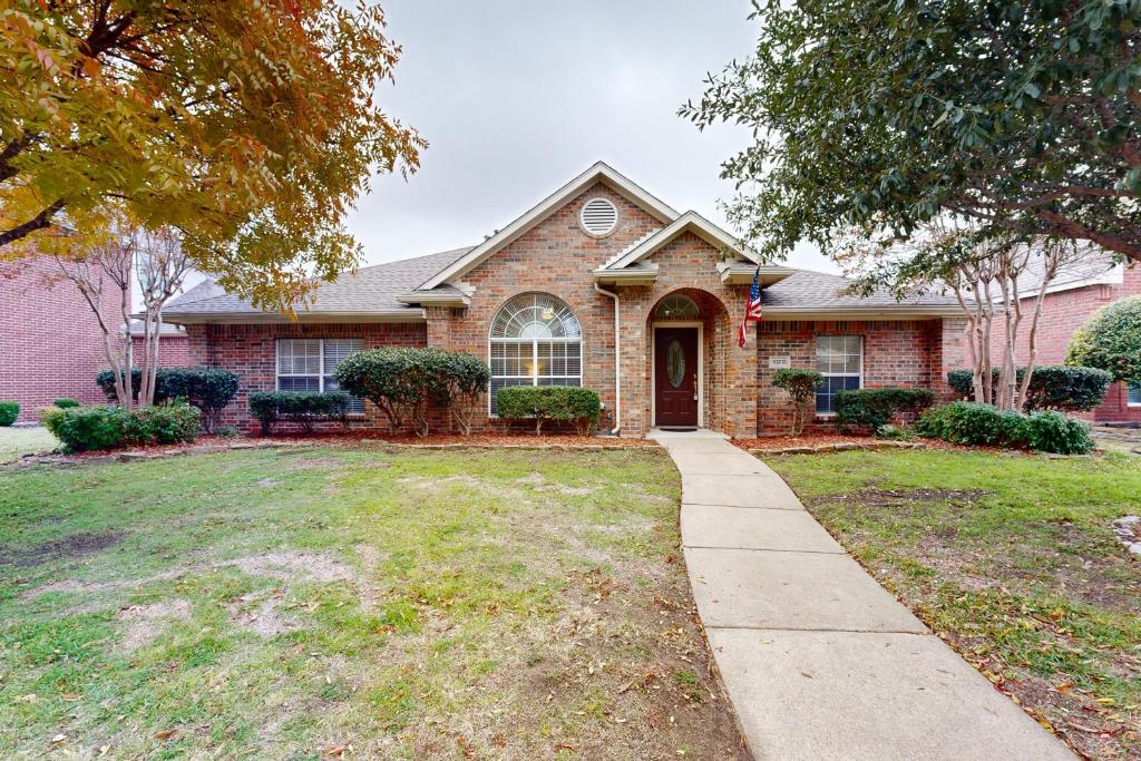 a brick house with a sidewalk in front of it at Games, Backyard & Patio: Spacious Home in Frisco in Frisco