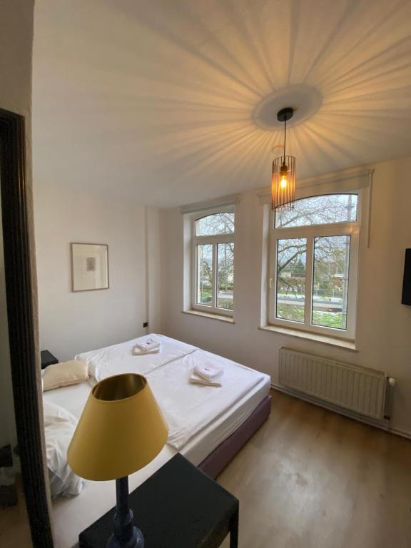 a bedroom with a bed and a lamp and two windows at Tanne Grand Palace in Alleringersleben