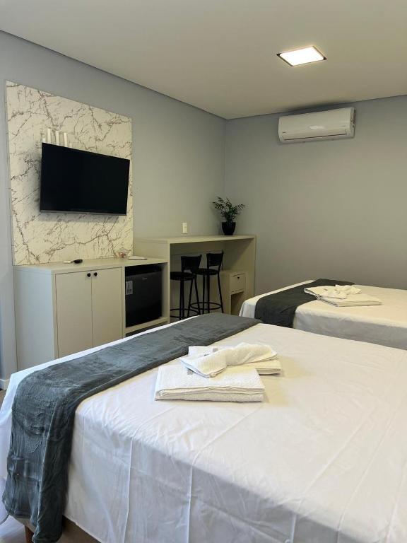 a hotel room with two beds and a tv on the wall at Pousada Selenita in Ametista do Sul