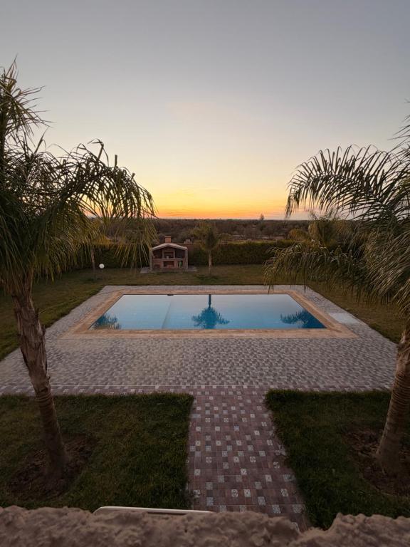 a swimming pool with a sunset in the background at villa lina in Aït Mazou