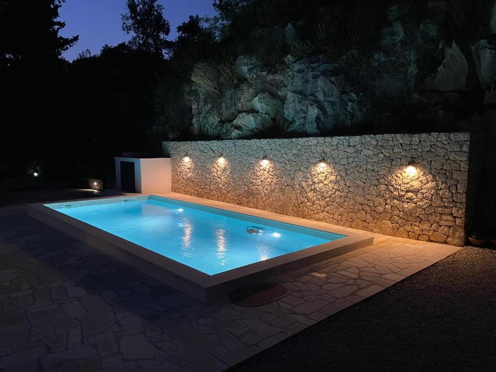 a swimming pool with lights on a stone wall at House Damić in Korčula