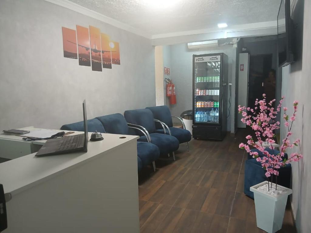 a living room with blue couches and a desk at FIRMH HOSTEL CAFE DA MANHA incluso e traslado in Guarulhos