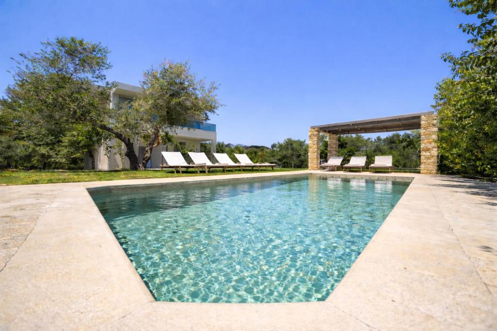 a swimming pool with some chairs and a building at Luxury Villa Marian with Private Pool and Jacuzzi near the Beach of Georgioupoli in Georgioupolis