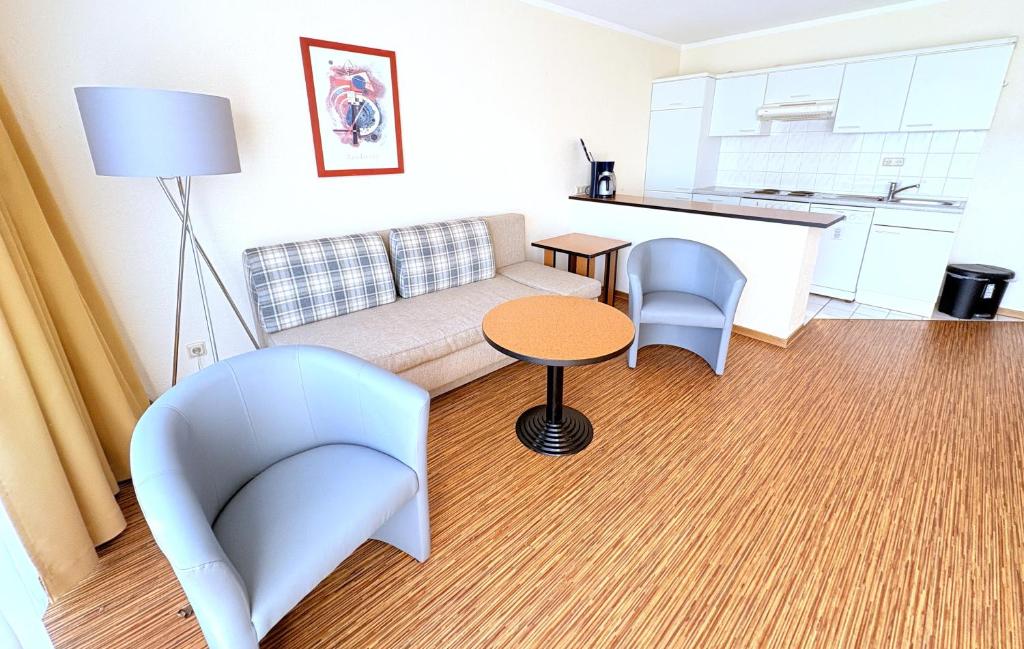 a living room with a couch and chairs and a table at Boddenhof Apartment 46 - ebenerdig, tierfreundlich in Buschvitz