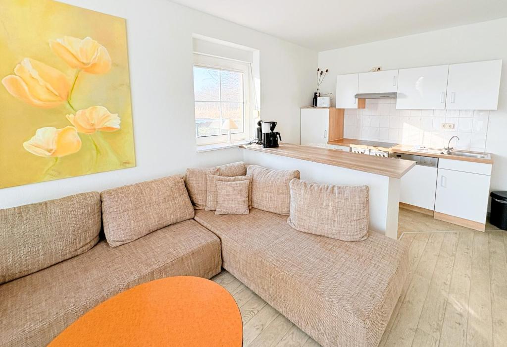 a living room with a couch and a kitchen at Boddenhof Apartment 50 - modern und freundlich, viel Sonne in Buschvitz