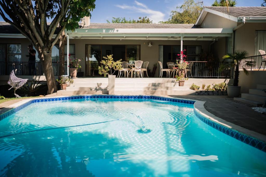 a swimming pool in front of a house at De Wingerd Wijnland Lodge in Paarl