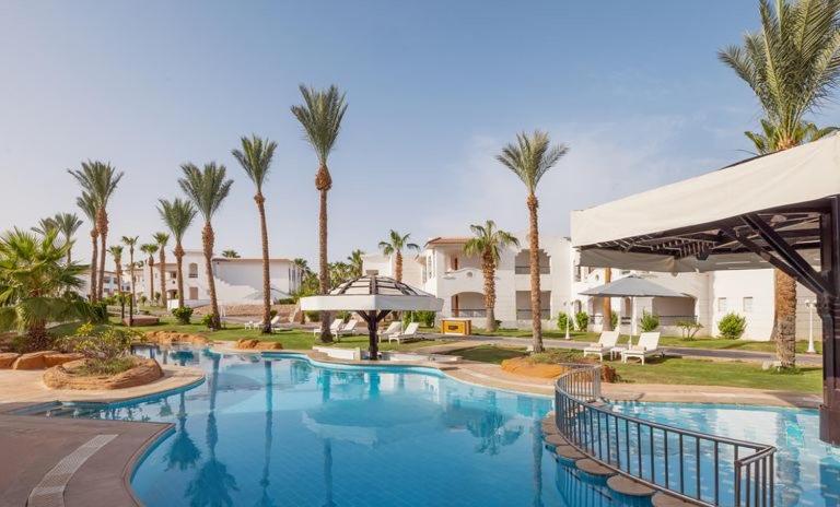a large swimming pool with palm trees in a resort at Private Luxury Villas at Sharm Dreams Vacation Club in Sharm El Sheikh
