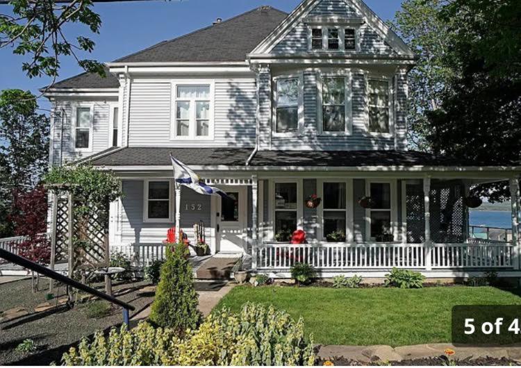 a white house with a porch and an american flag at Hilltop Landing in Digby