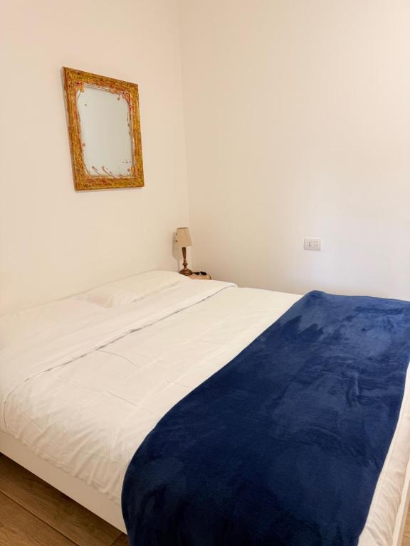 a white bed with a blue blanket on top of it at Valdagno 11 B&B in Busto Arsizio
