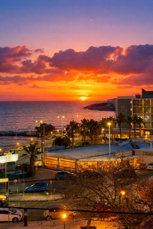 a sunset over a city with a parking lot and the ocean at Blue Horizon Gem On The Port in Rafina