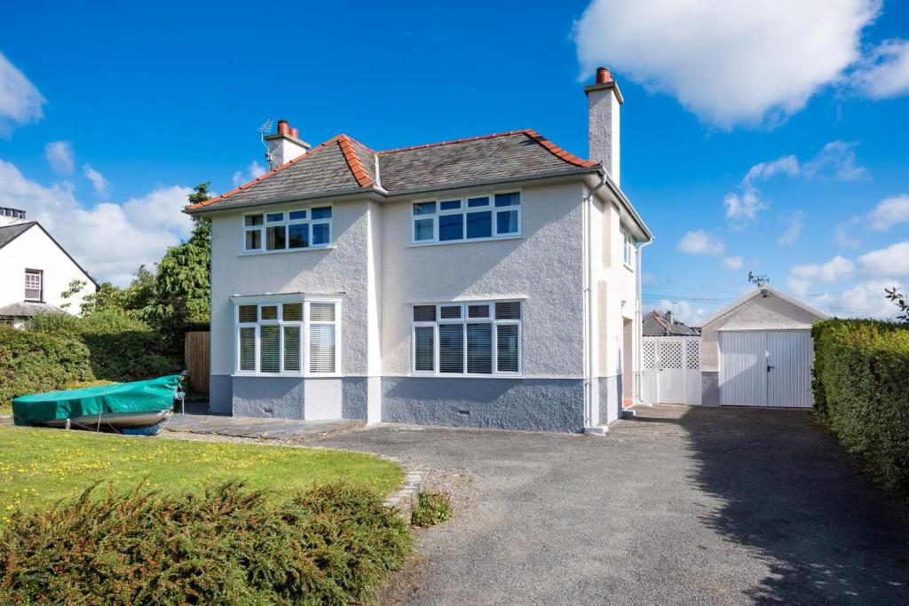 a white house with a boat in the driveway at 4 Bed in Abersoch oc-dolwar in Abersoch
