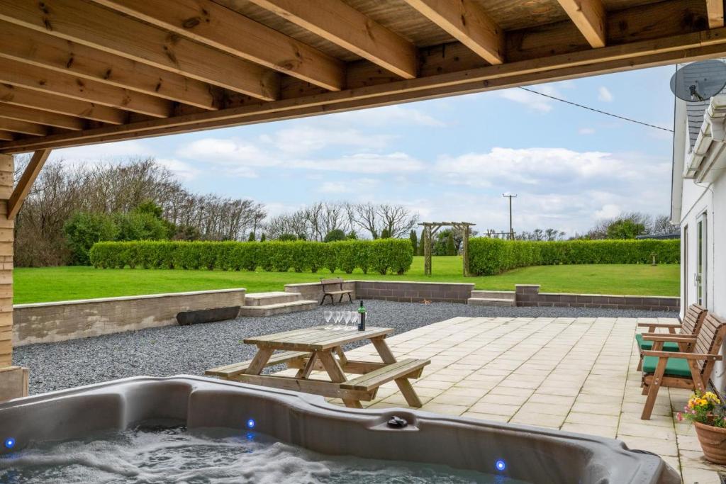 a patio with a hot tub and a picnic table at 5 Bed in Bryncroes oc-llecyn in Pwllheli