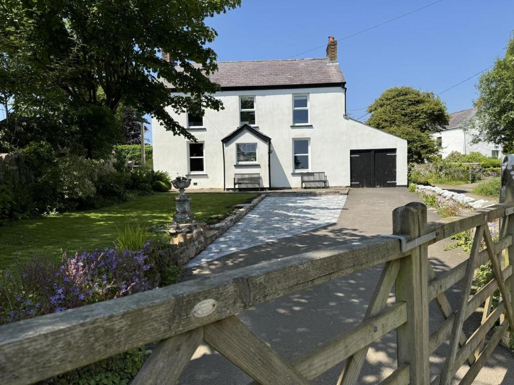a wooden fence in front of a white house at 5 Bed in Gower oc-hh101 in Port-Eynon