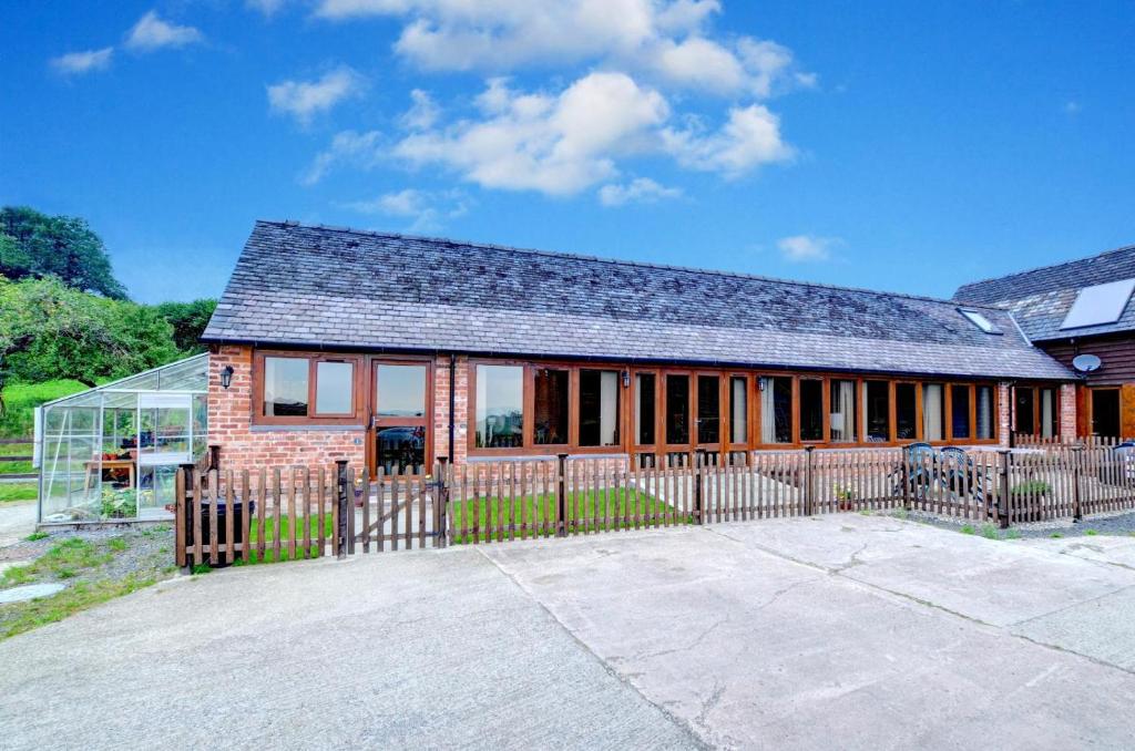 a brick house with a fence in front of it at 2 Bed in Welshpool oc-wab256 in Berriew