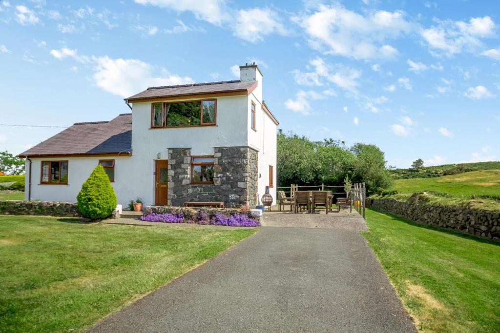 a white house with a patio and a table at 3 Bed in Pwllheli oc-penmae in Pwllheli