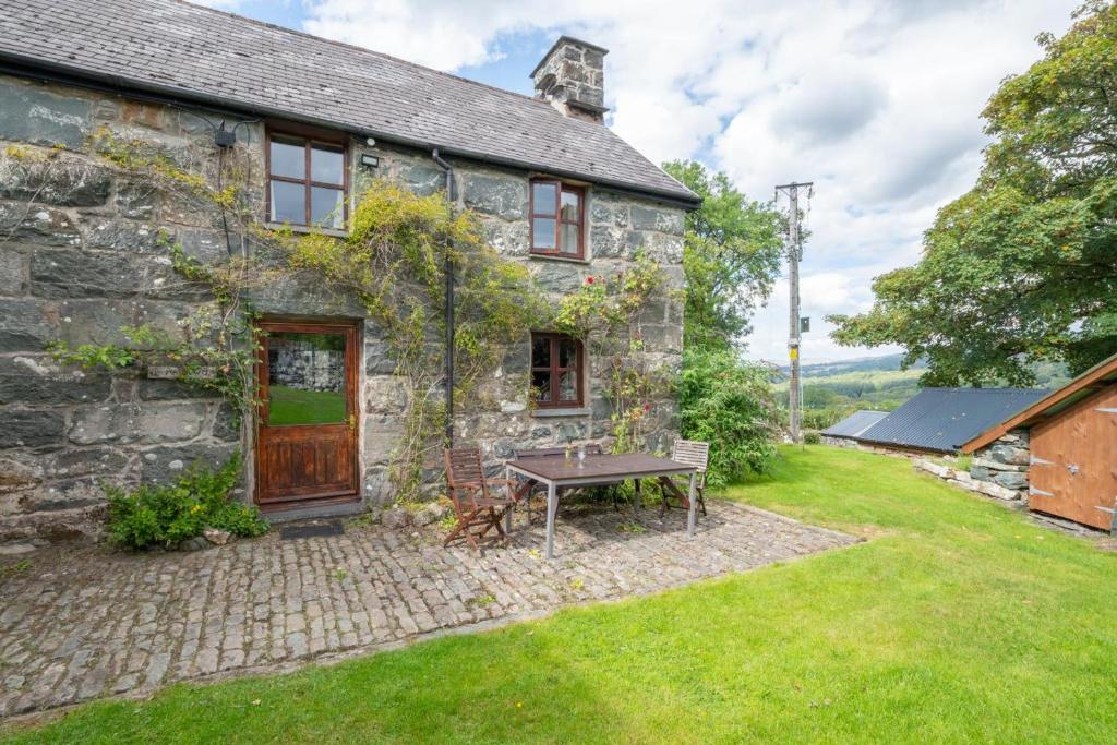 an old stone house with a picnic table in the yard at 3 Bed in Dolgellau oc-wah569 in Llanfachreth