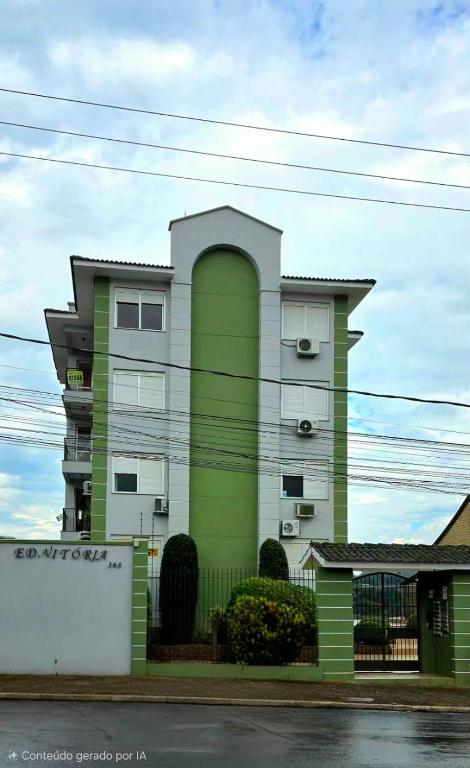 a green and white building in front of a building at Apto térreo aconchego e localização central in Santa Rosa