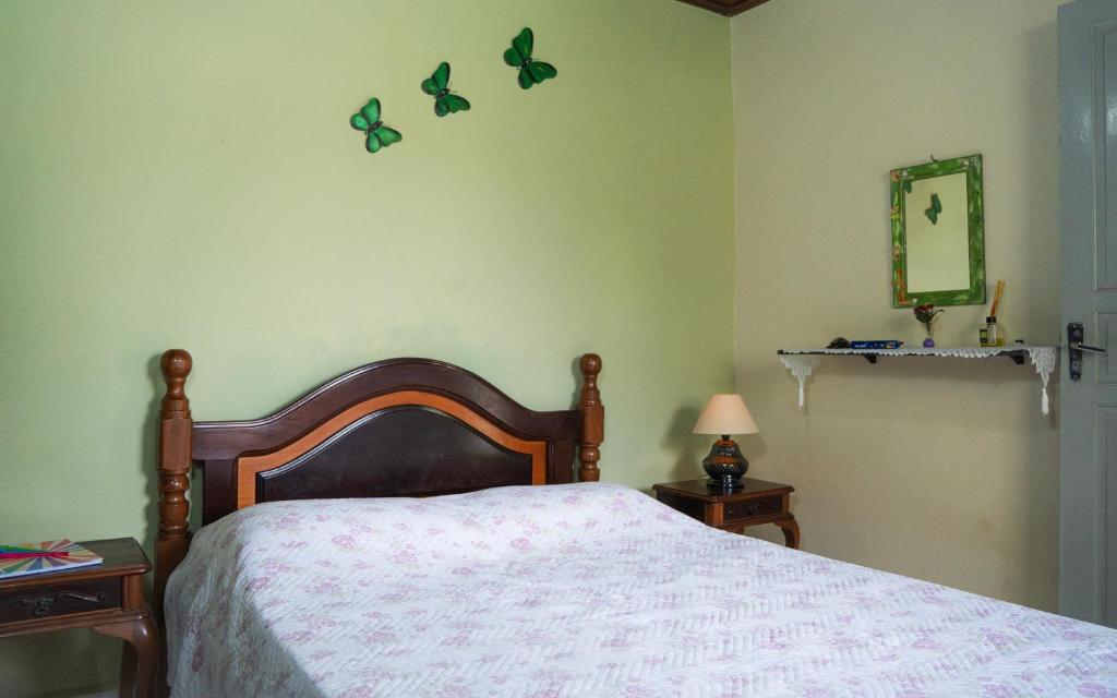 a bedroom with a bed with butterflies on the wall at SUÍTE em casa FRENTE AO MAR - Acesso à PRAIA, CHURRASQUEIRA, GARAGEM e WI-FI 80mbps - Ambiente Privativo - Itanhaém-SP in Itanhaém