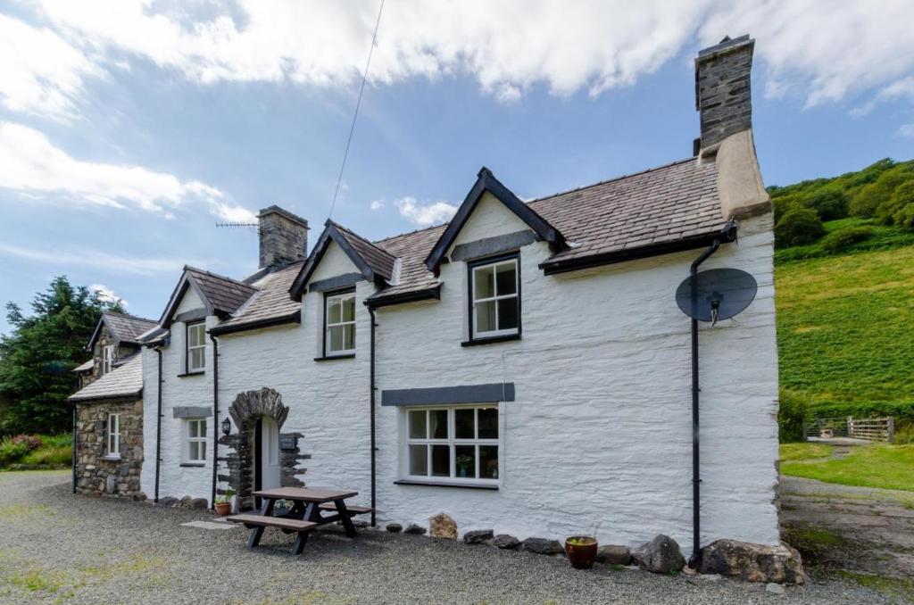 a white house with a picnic table in front of it at 3 Bed in Tywyn oc-bow248 in Abergynolwyn