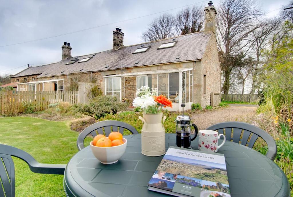 a table with a bowl of oranges on it in front of a house at 2 Bed in Berwick-upon-Tweed oc-nb678 in Lowick