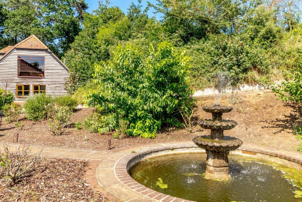 a fountain in a garden with a house in the background at 2 Bed in Woodbridge oc-vav in Hollesley