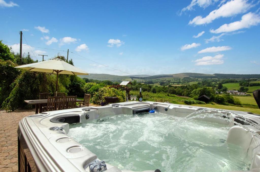 a hot tub in a backyard with an umbrella at 4 Bed in Cray oc-bow288 in Cray
