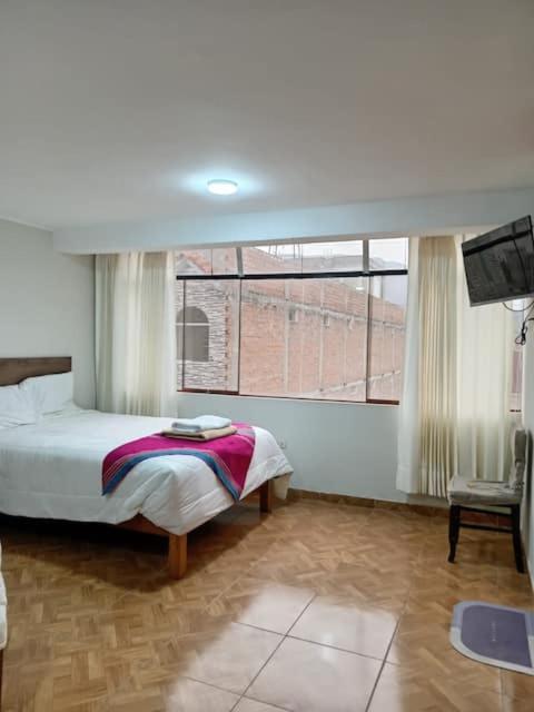 a bedroom with a bed and a large window at Hospedaje Samay Lodge - autogestionado in Chivay