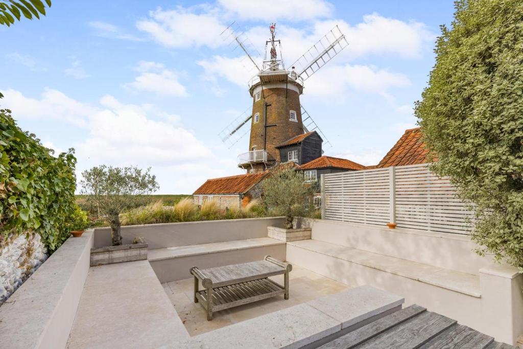 a bench in front of a building with a windmill at 4 Bed in Cley oc-m33116 in Cley next the Sea