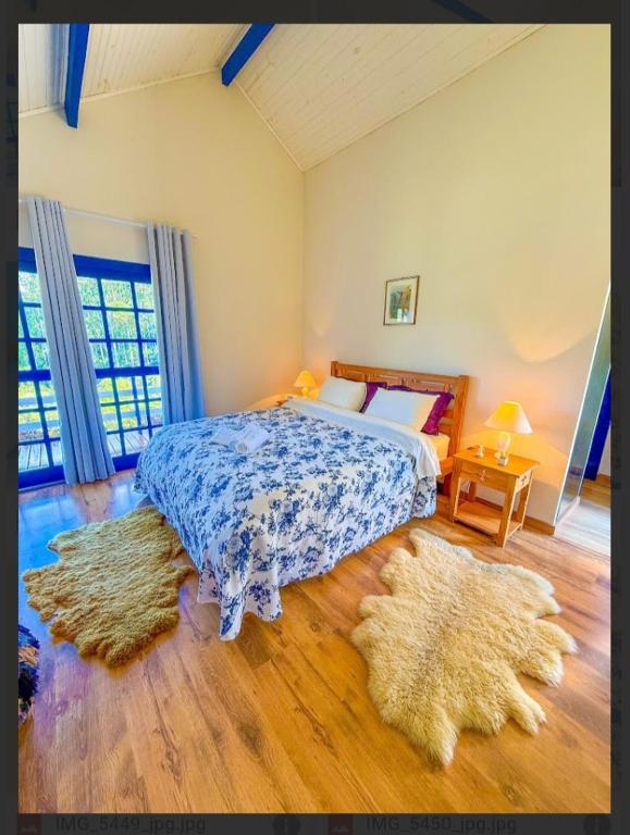 a bedroom with a bed and two rugs on the floor at Quinta dos Faisões in Santo Antônio do Pinhal