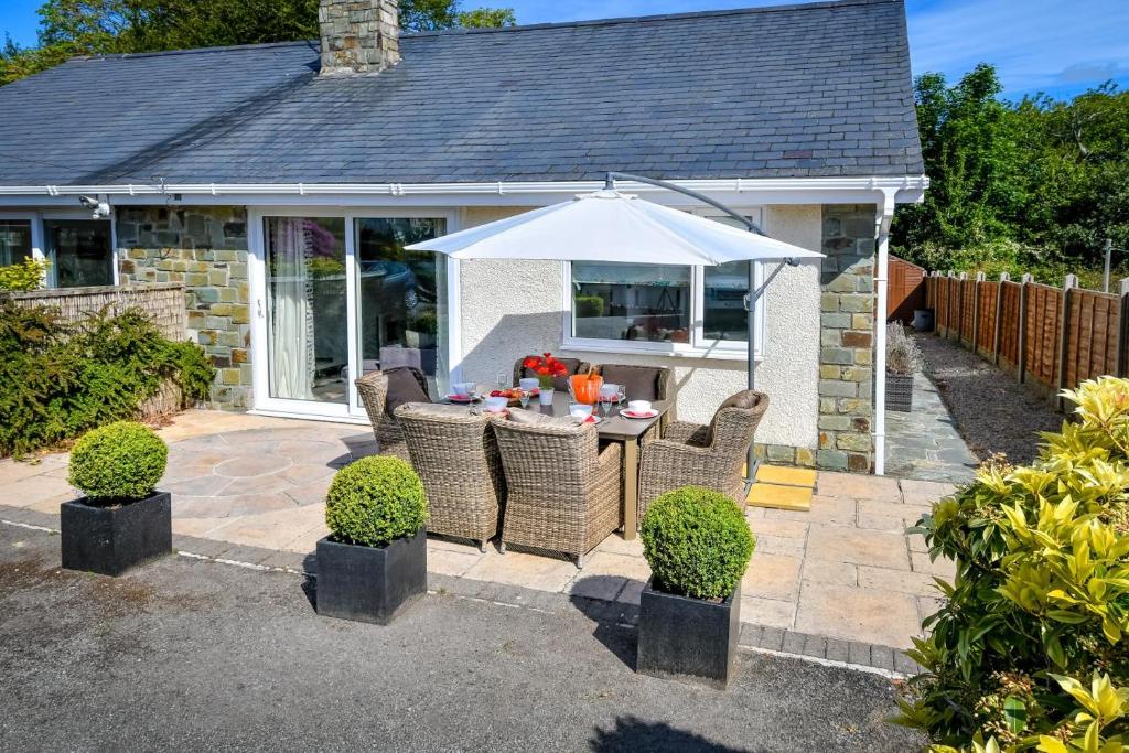 a patio with a table with an umbrella at 3 Bed in Pwllheli oc-hillvi in Llanbedrog