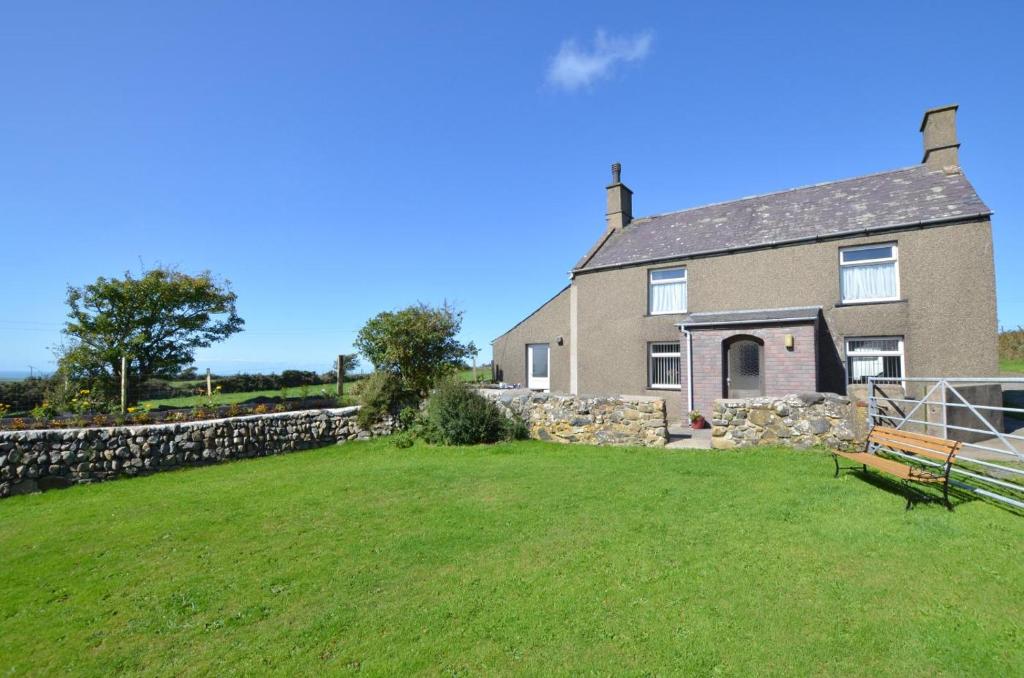 a house with a stone wall and a bench in the yard at 3 Bed in Pwllheli oc-wag486 in Bryncroes