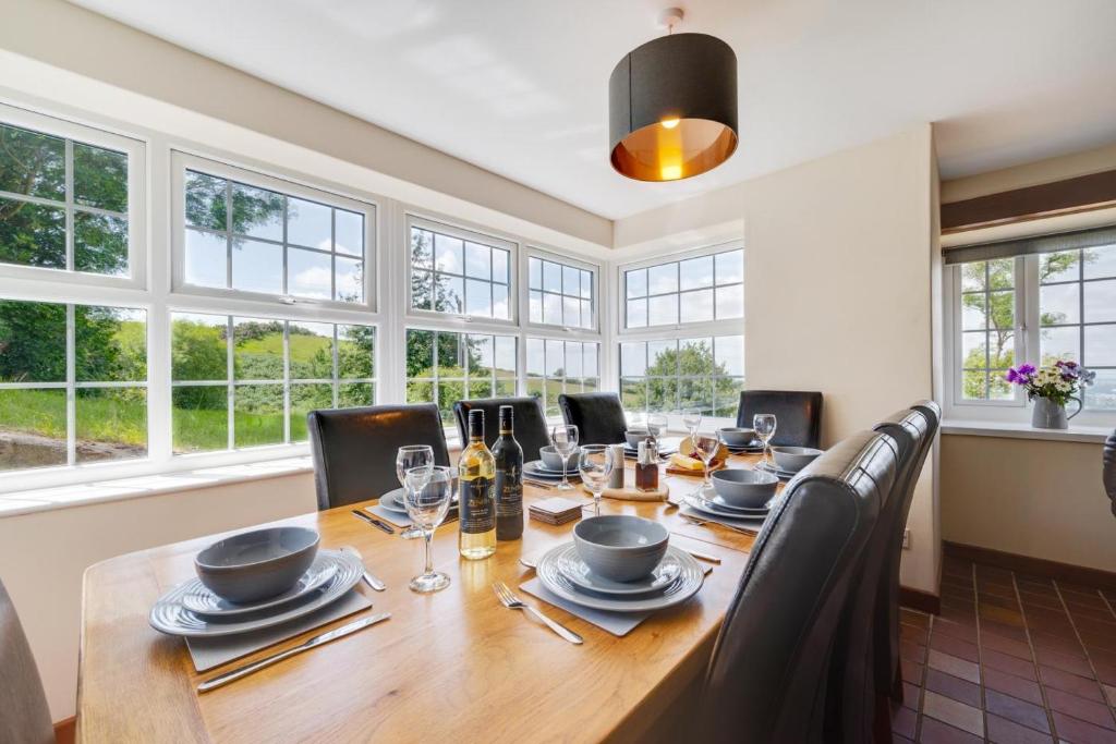 a dining room with a large wooden table and windows at 3 Bed in Llanllechid oc-wag712 in Llanllechid