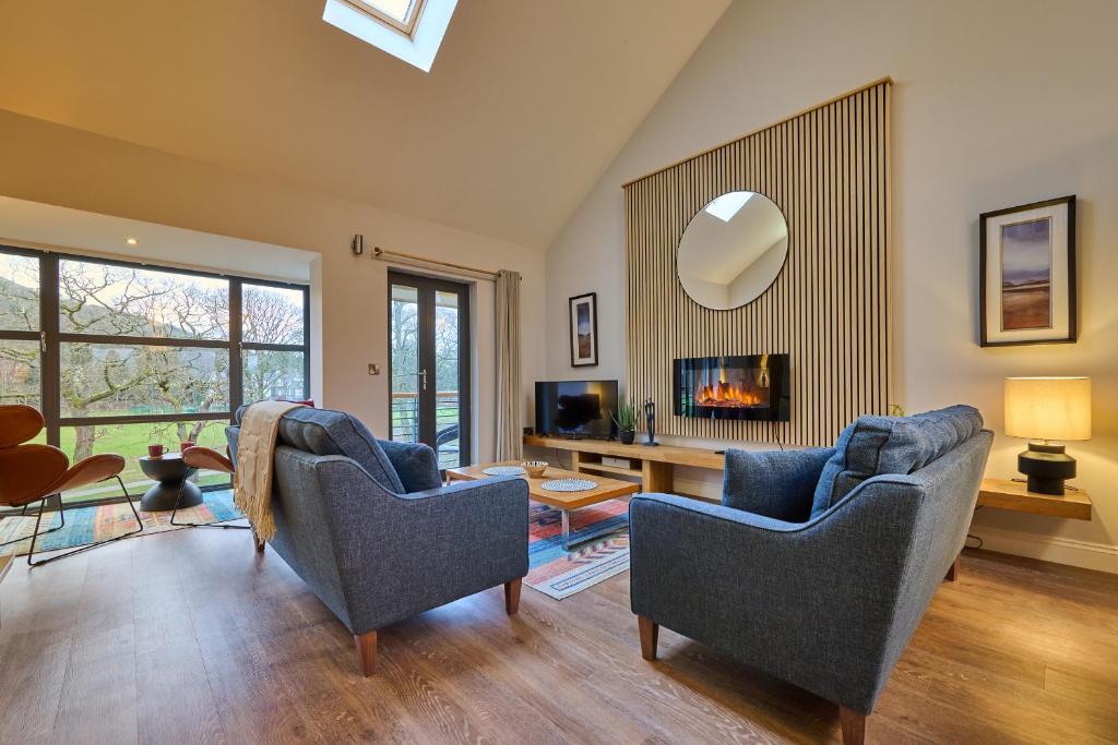 a living room with two blue chairs and a mirror at Riverside Park 5 in Keswick
