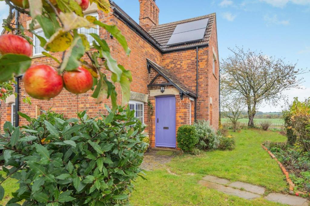an old brick house with a purple door and an apple tree at 3 Bed in Fulbeck oc-v33643 in Fulbeck